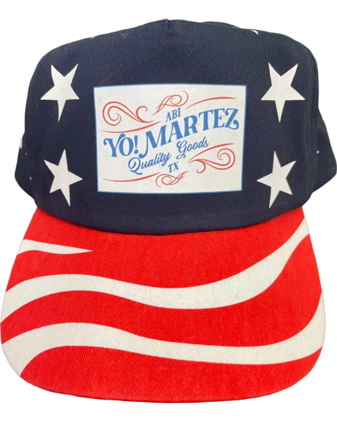 A patriotic trucker hat with a stars pattern on the crown and a striped visor, featuring a YO! MARTEZ logo in the center.