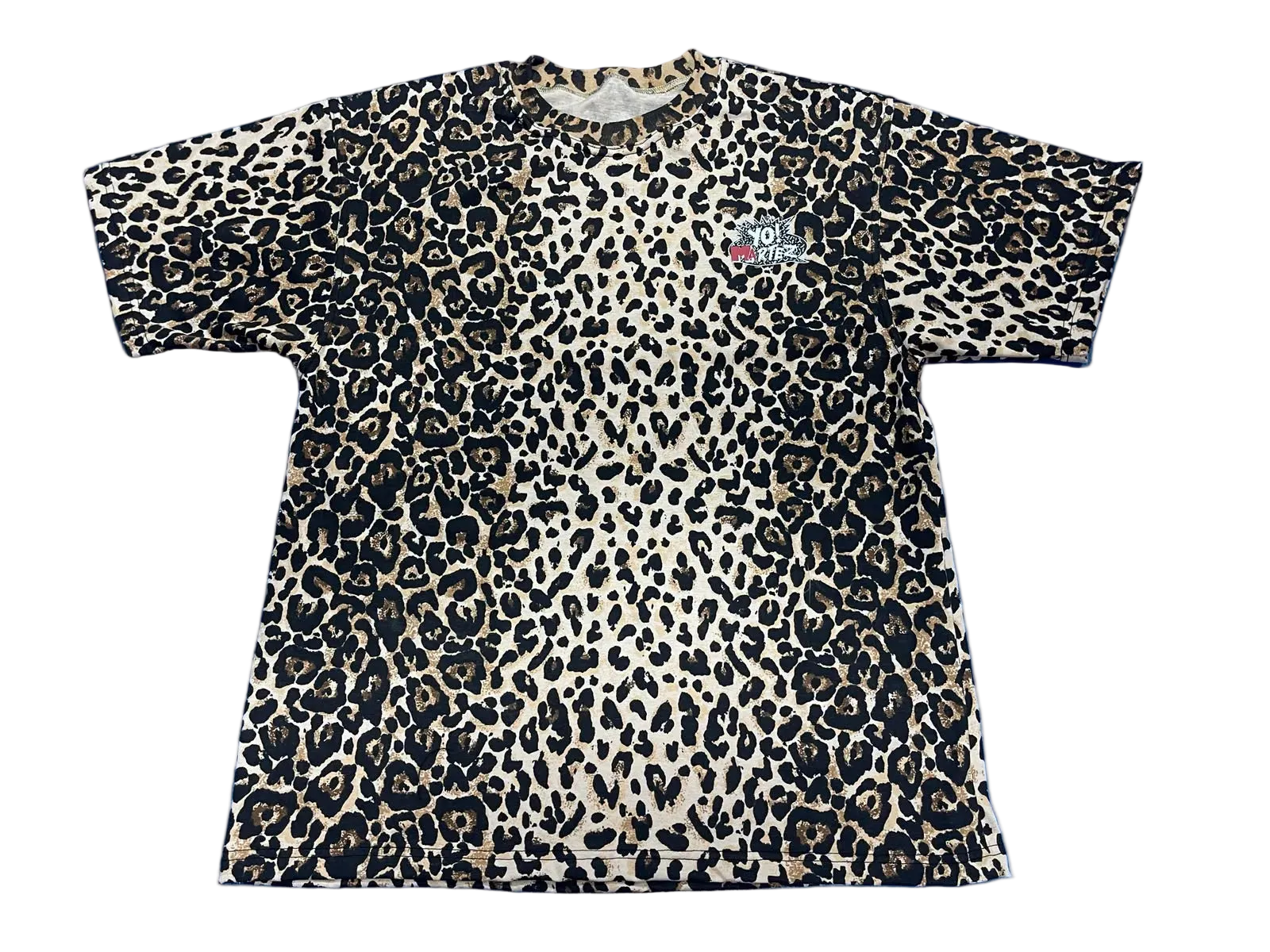 A short-sleeve crewneck t-shirt featuring a leopard print pattern in black, beige, and brown, with a small graphic on the left chest.