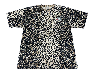 A short-sleeve crewneck t-shirt featuring a leopard print pattern in black, beige, and brown, with a small graphic on the left chest.