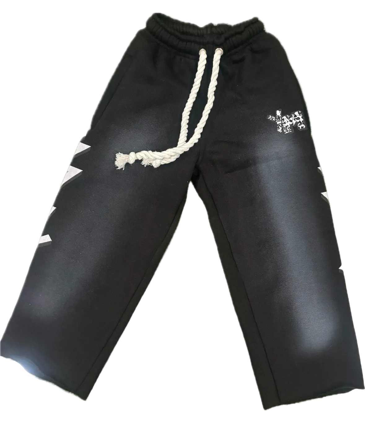 Black sweatpants with a white braided drawstring, white zigzag side cutouts, and a small white graphic on the upper right leg, shown against a plain white background.