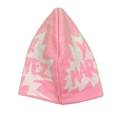 A pink knit beanie hat featuring a white and pink knit pattern with stylized text and starburst shapes, shown against a plain white background.