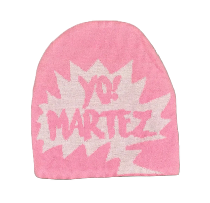 A pink knit beanie hat featuring a white comic-style burst graphic with the text 'YO! MARTEZ' in pink, shown against a plain white background.