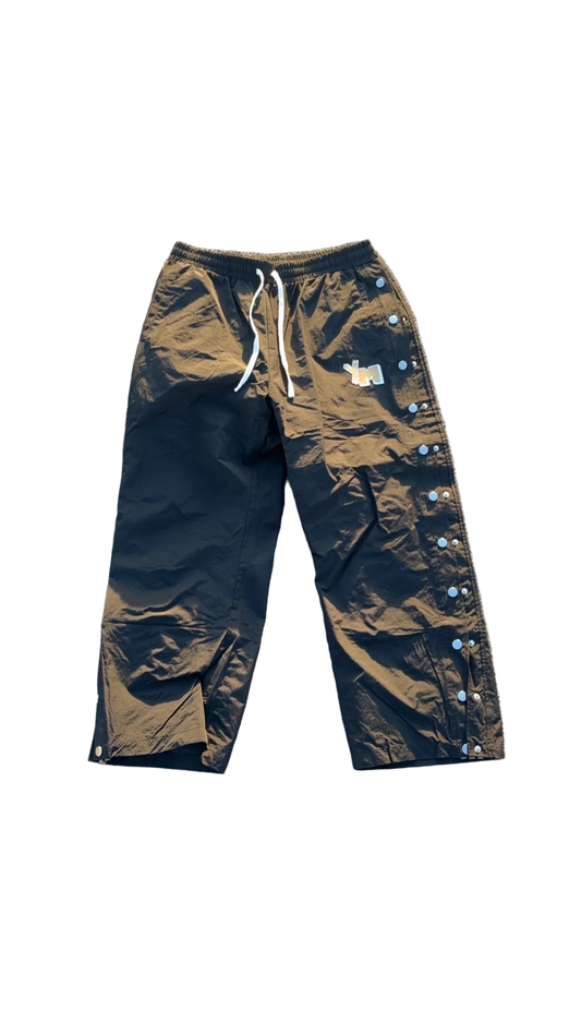 A pair of black track pants with an elastic waistband and drawstring, featuring three embroidered stripes on the leg, displayed on a flat surface.