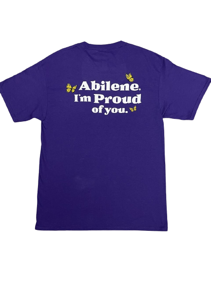 A purple shirt shown from the back, featuring the text 'Abilene. I'm Proud of you.